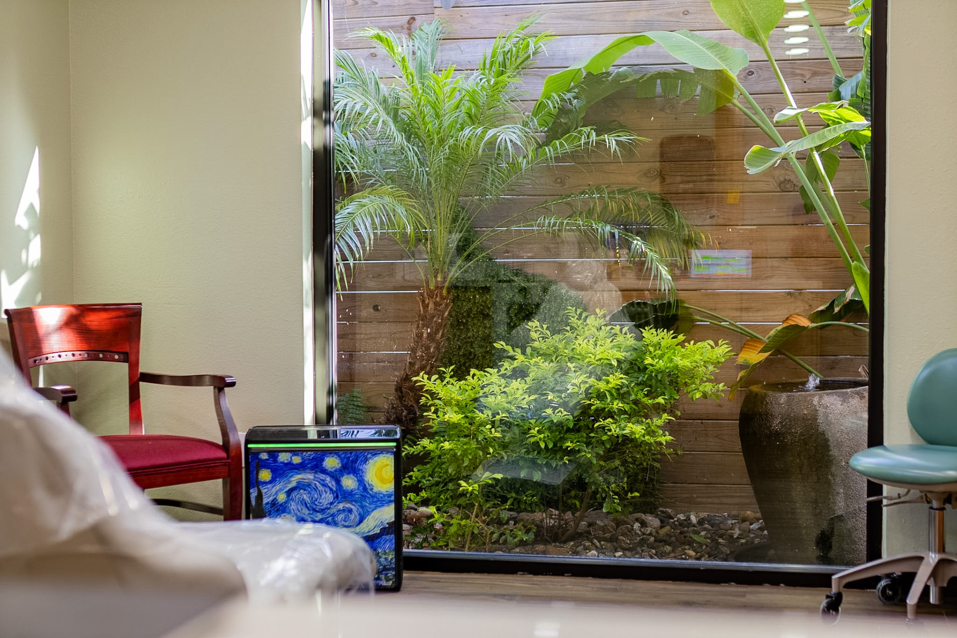 A treatment room with a floor-to-ceiling window looking onto a tropical garden