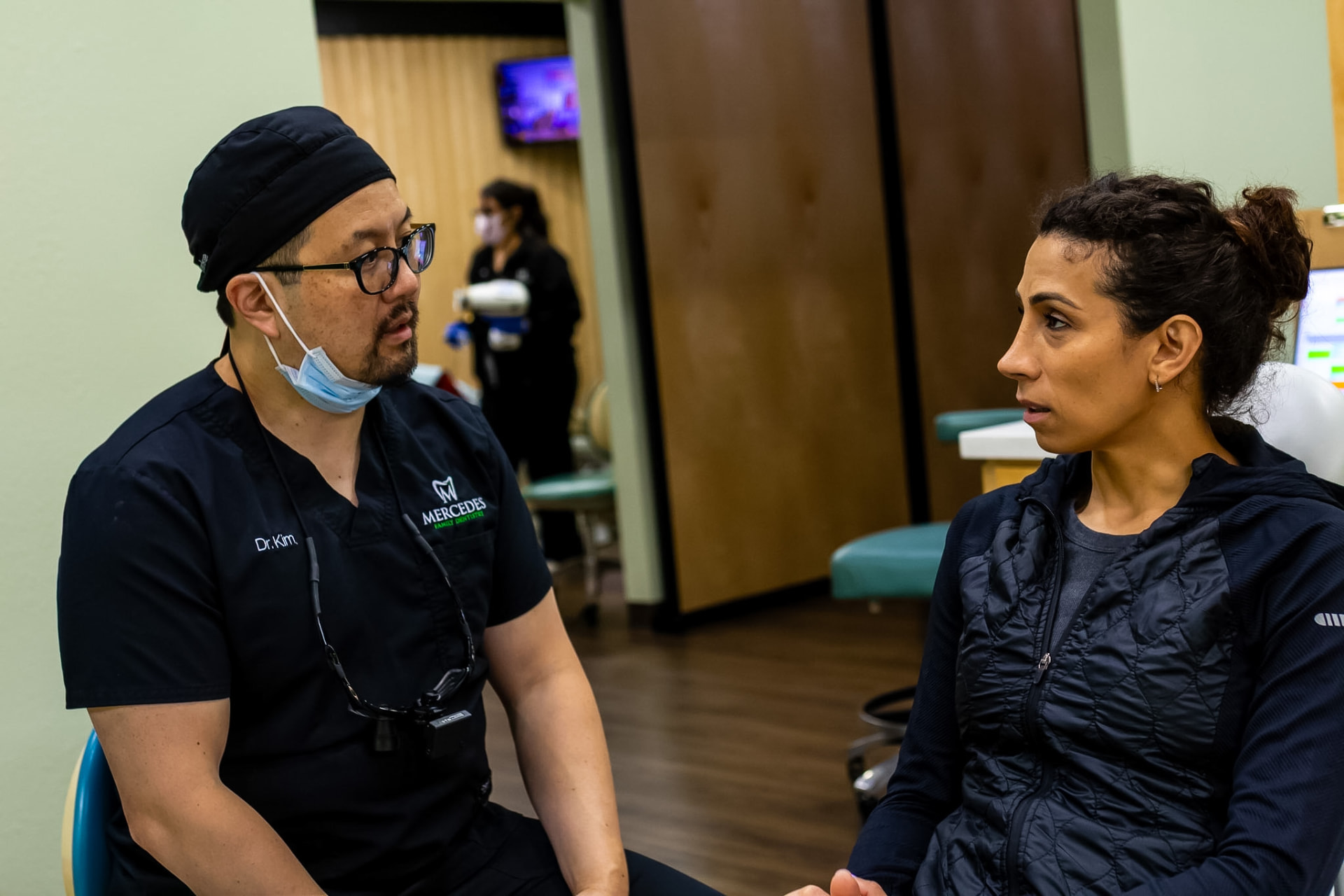 Dr. Kim listening to a patient in a treatment room