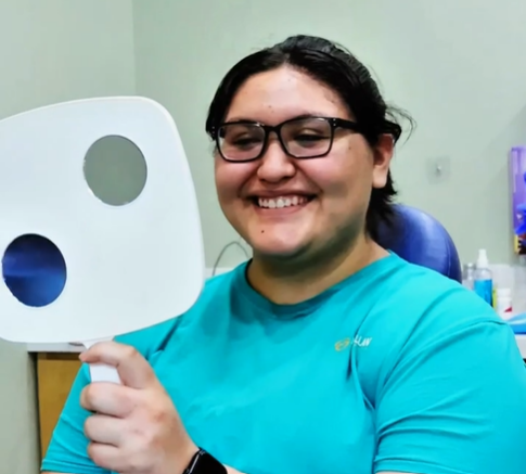 A smiling patient viewing her smile in a mirror